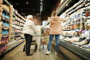 Older adult pushing a cart in the grocery store.