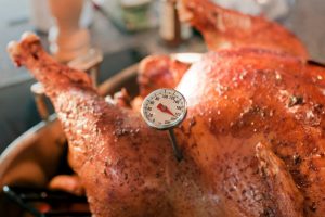 A thermometer reading approximately 190°F in a cooked chicken.